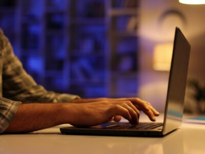 A young Arab student works on his laptop in the evening in the living room. A man with a beard works